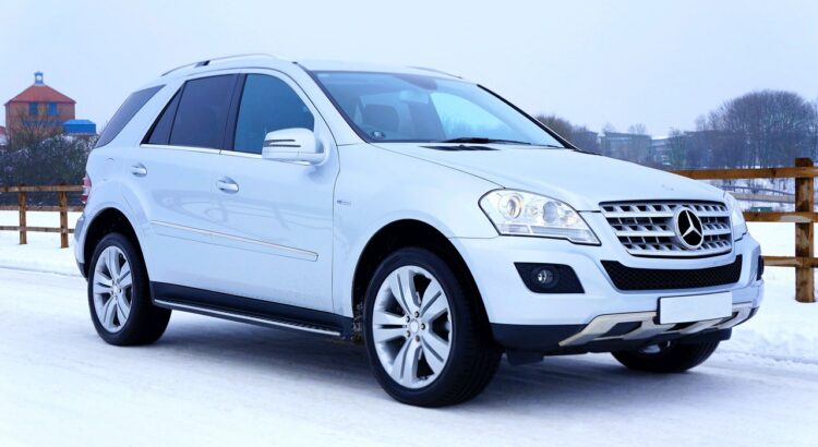 Une voiture blanche sur la neige. Elle porte un pneu hiver pour SUV